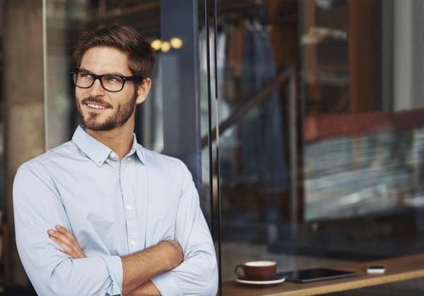 A young man standing and staring with eyeglasses